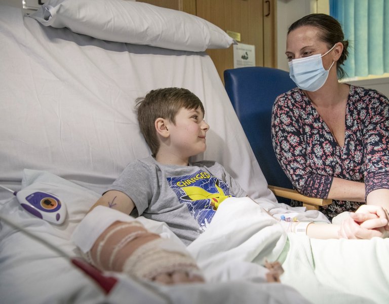 Boy in hospital bed being comforted by his mum
