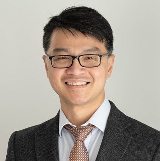 A man wearing glasses in a suit and tie smiling