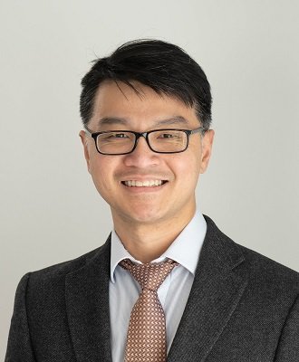 A man wearing glasses in a suit and tie smiling