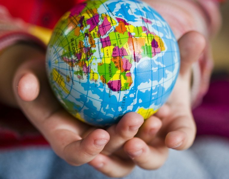 A child's hand holding a globe